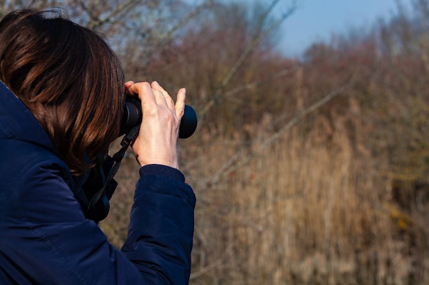 写真 鳥を見ている双眼鏡を持つ女性