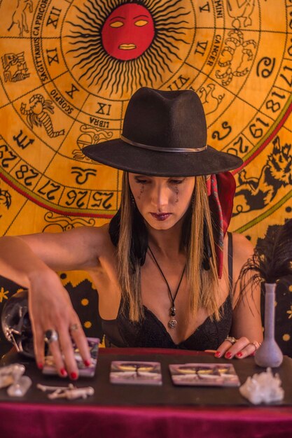 woman with a black hat and runic letters written on her face putting the tarot cards on the table