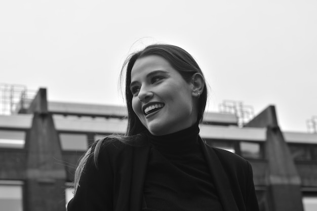 A woman with a black turtleneck and a black turtleneck smiles at the camera.