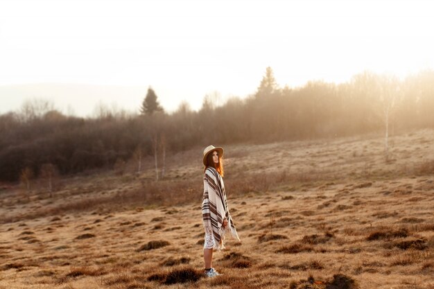 Photo woman with a blanket and a hat in a dry meadow