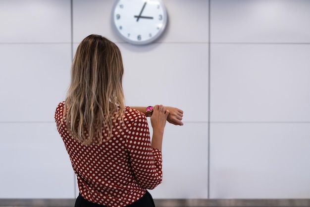 Woman with the blonde hair looking your clock in airport