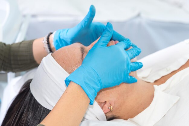 Photo woman with blue gloves performs facial cleansing in a beauty center