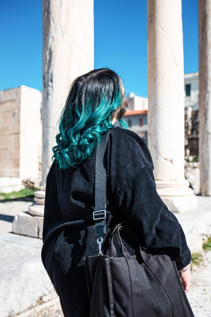 파란 머리를 한 여자가 고대 도시의 폐허를 걷고 있습니다.