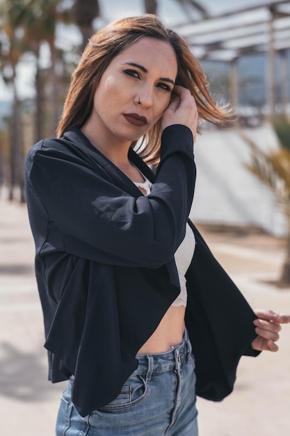 Woman with blue outfit looking at camera touching her blazer and hair