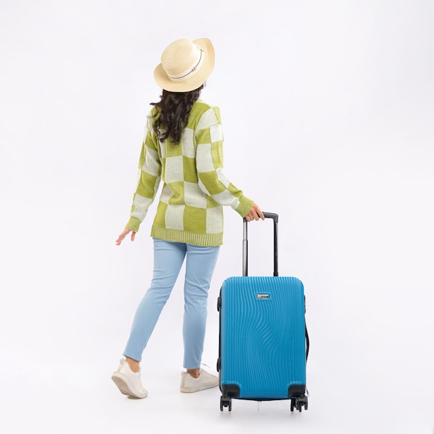 A woman with a blue suitcase is walking with her back to the camera.