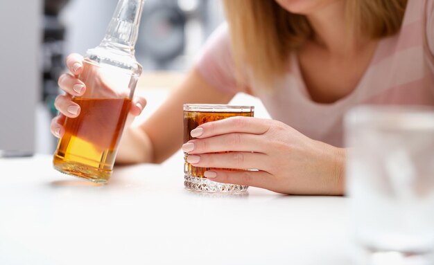 Photo woman with bottle of alcohol and glass alone