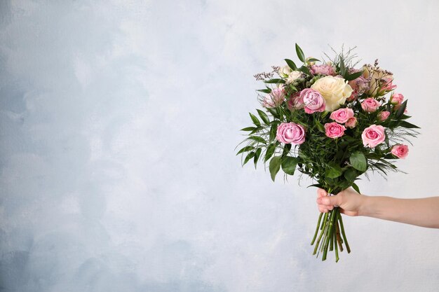 Woman with bouquet of beautiful roses on light blue background closeup Space for text