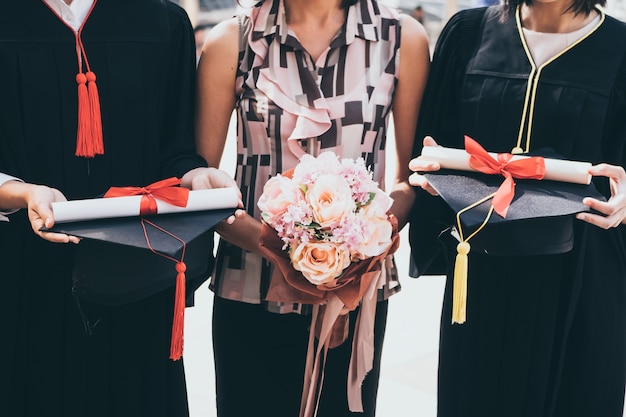 Foto una donna con il mazzo si congratula per la sua famiglia il giorno della laurea, concetto di successo