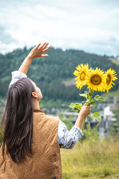 Woman with a bouquet of sunflowers in nature in a mountainous area