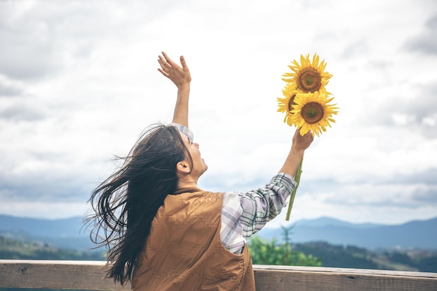 山の自然の中でひまわりの花束を持つ女性