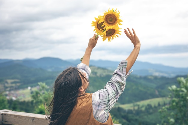 山の自然の中でひまわりの花束を持つ女性