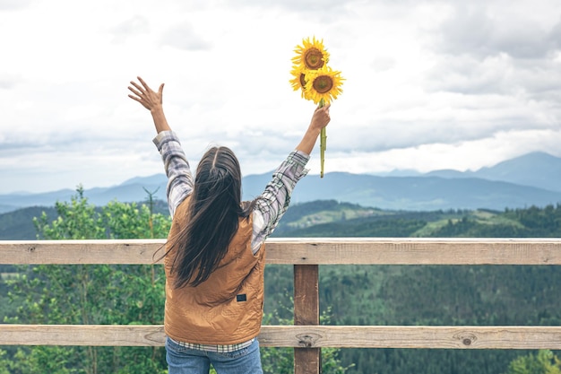 Donna con un mazzo di girasoli in natura in montagna