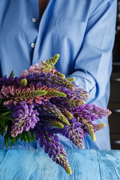 野生のルピナスの花の花束を持つ女性