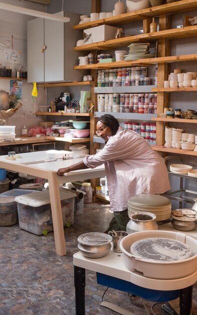 Foto donna con i capelli intrecciati al suo studio di ceramica d'arte a casa tabella mobile