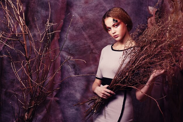 Woman with bright make up with dry branches