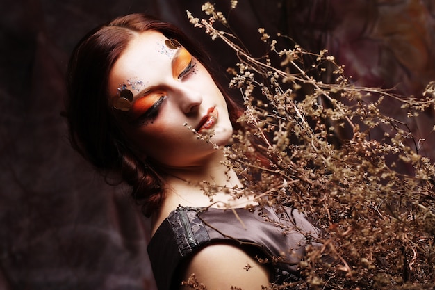 Woman with bright make up with dry branches