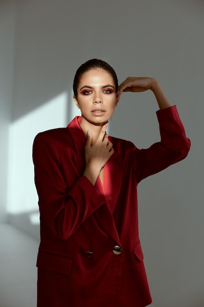 Женщина с ярким макияжем на лице, красная куртка, украшение, роскошная модель