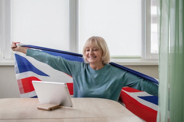 Woman with british flag watches broadcast of platinum jubilee of queen celebrations online at home