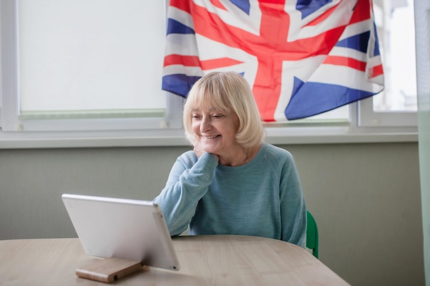 영국 국기를 든 여성이 집에서 온라인으로 여왕의 플래티넘 쥬빌리 방송을 시청합니다.