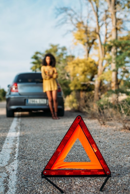 Woman with broken car and triangle