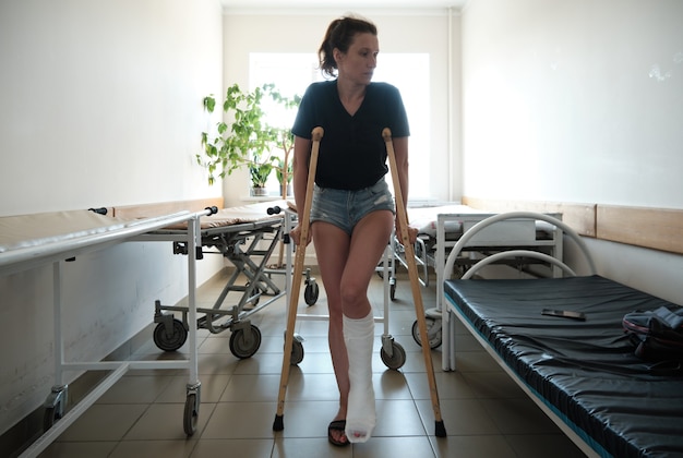 A woman with a broken leg uses orthopedic crutches leg injury\
rehabilitation after a fracture