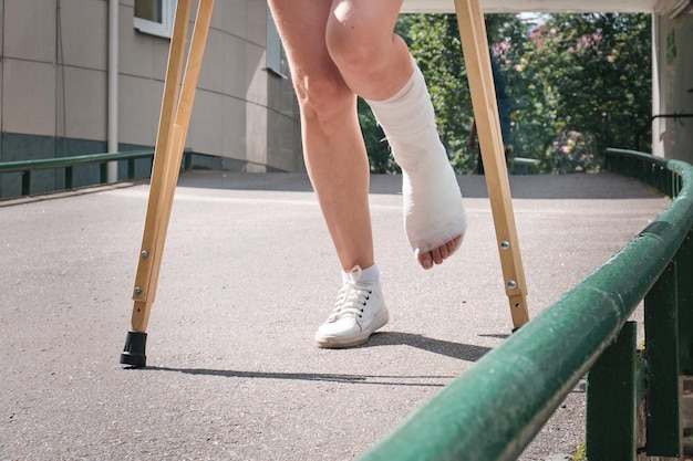 Foto una donna con una gamba rotta cammina giù per una rampa usando stampelle ortopediche