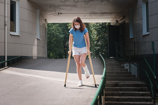 다리가 부러진 여성이 정형 목발을 사용하여 경사로를 걷고 있습니다.