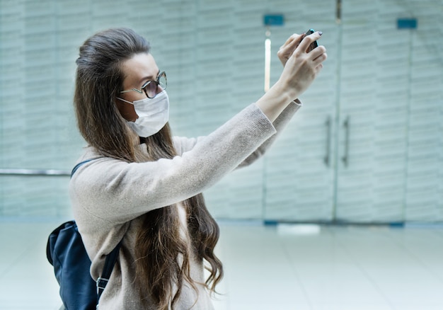 Женщина с каштановыми волосами в медицинской маске из-за загрязнения воздуха или вирусной эпидемии в городе.