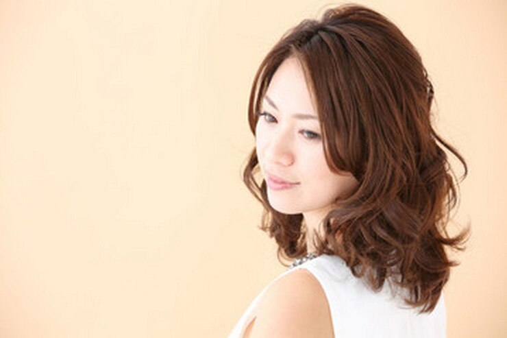 Photo 茶色のと白いドレスを着た女性がベージュの背景に立っています