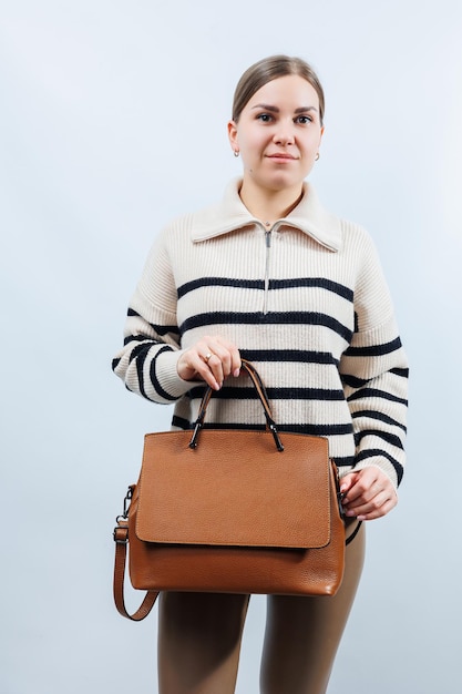 白い背景で隔離の茶色の革のバッグを持つ女性スタイリッシュなクラッチバッグクローズアップ垂直写真