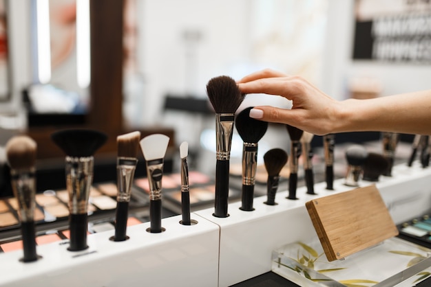 Photo woman with brush choosing shadows tone in cosmetics store. buyer in luxury beauty shop salon, female customer in fashion market