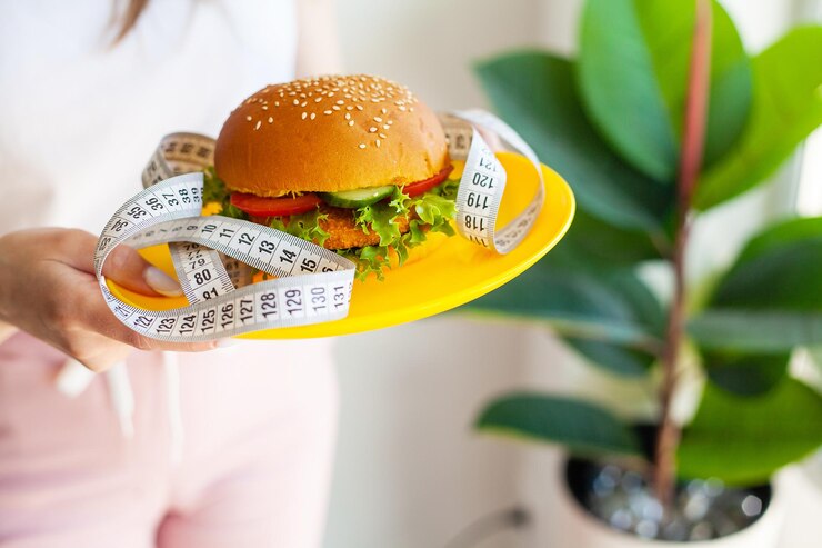 Photo woman with burger and measuring tape while dieting
