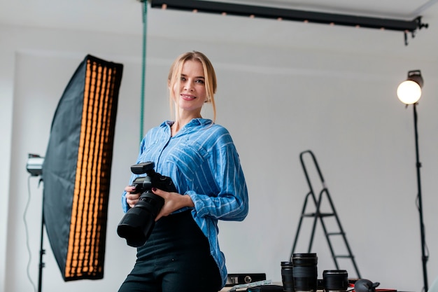 Photo woman with camera preparing the studio for a shooting