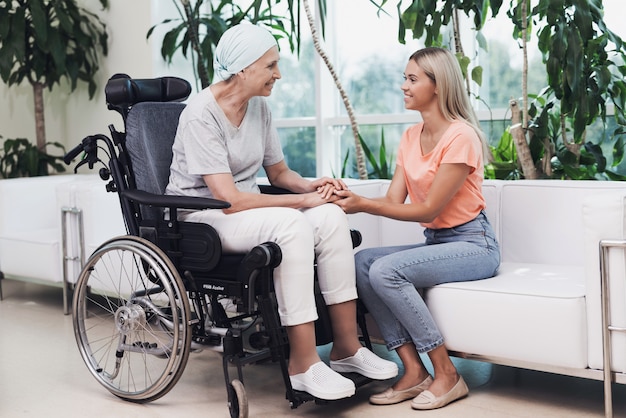 Una donna con un cancro è seduta su una sedia a rotelle