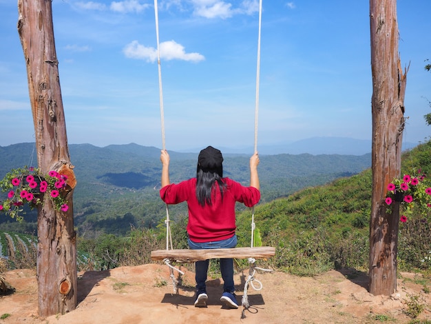 Photo woman with casual clothes sitting on wooden swing on mountain