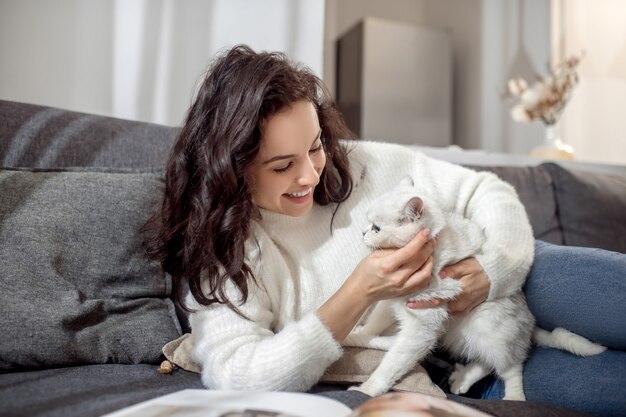 猫を抱く女性。素敵な白い猫と黒髪の若い女性