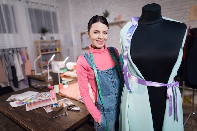 Woman with centimeter stands near the sewing.