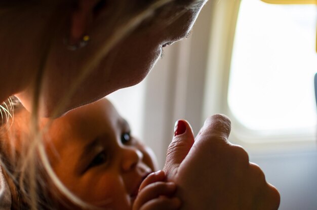 写真 飛行機の窓のそばで陽気な赤ちゃんを抱いた女性