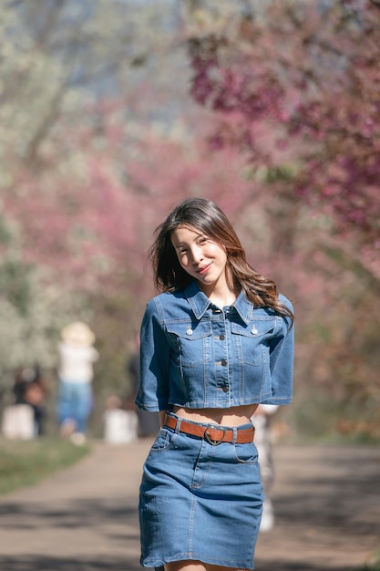 Donna con fiori di ciliegio o fiore di sakura che fiorisce nel parco