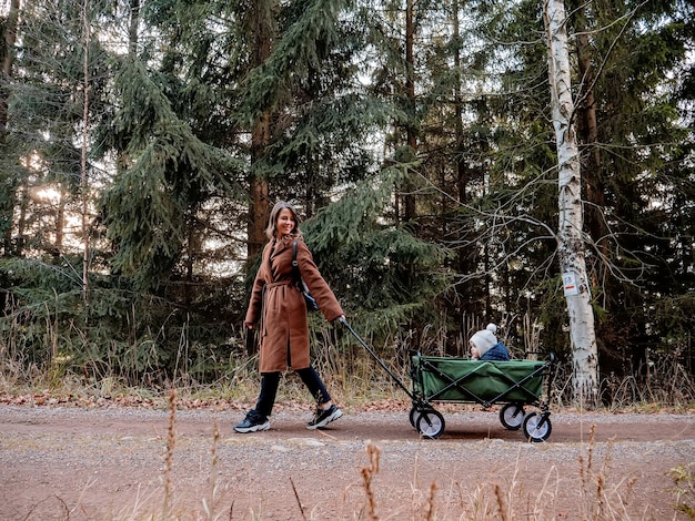 Woman with a child in a wagon walking down in the forest