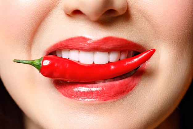 Woman with chili red pepper isolated en blue background sexy
female lips hot seductive girl