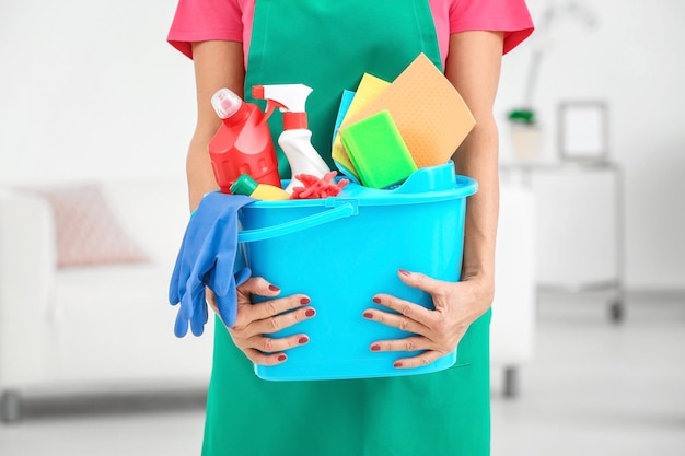 Woman with cleaning supplies at home closeup