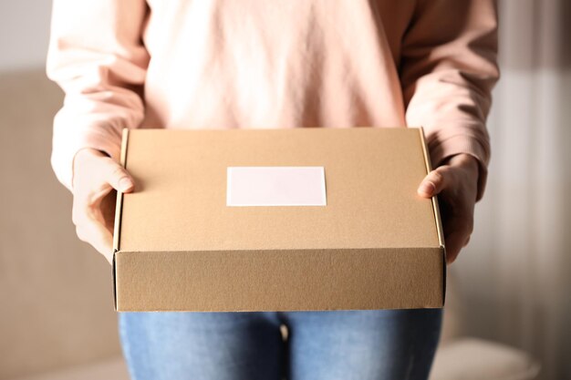 Woman with closed cardboard box at home closeup