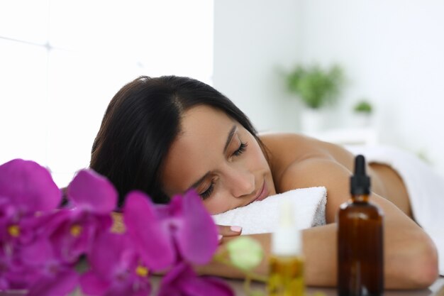 Woman with closed eyes lies on massage table in spa salon. Relaxation and relaxation after a working day concept