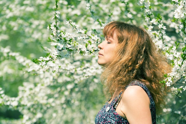 Woman with closed eyes smelling cherry blossoms