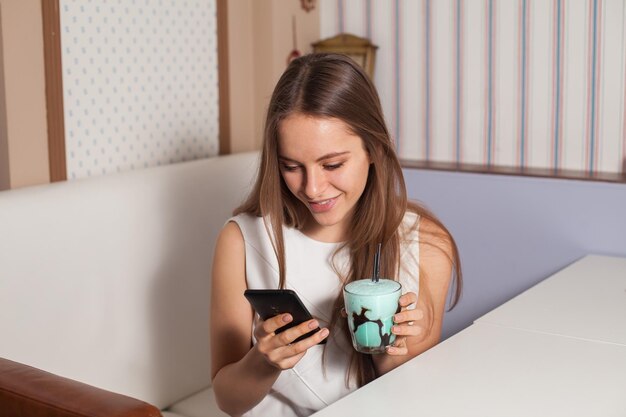 Woman with cocktail and cellphone in cafe