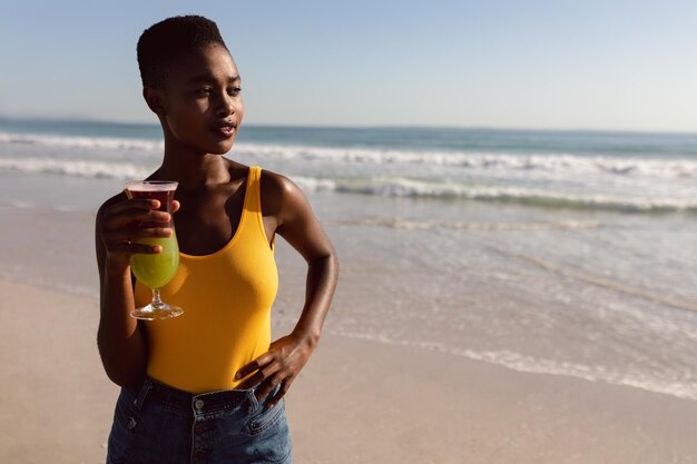 Woman with cocktail drink standing on the beach