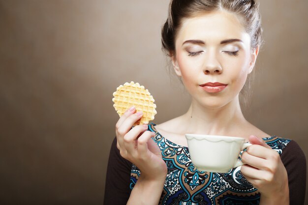 コーヒーとクッキーを持つ女性