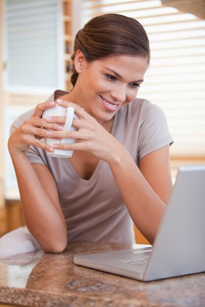 Donna con caffè e laptop in cucina