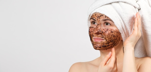 Foto una donna con una maschera al caffè sul viso si prende cura della sua pelle